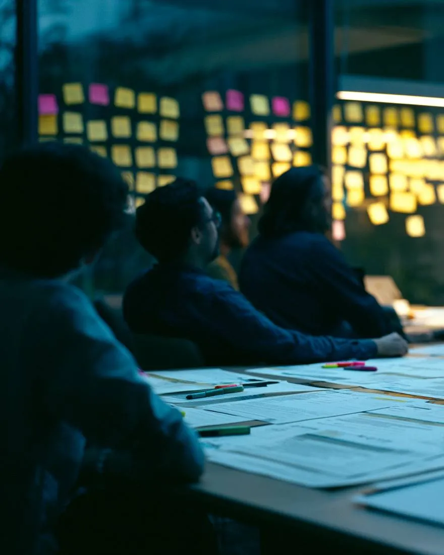 A bid team working late around a table covered in printed proposals